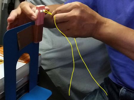 黄色の線が素材ラインを示す。ヤーン・ツイスターで撚り合わせ始めると、余りのラインが手の下で暴れるので、自由に動ける空間を取り、２本とも垂らしておく。